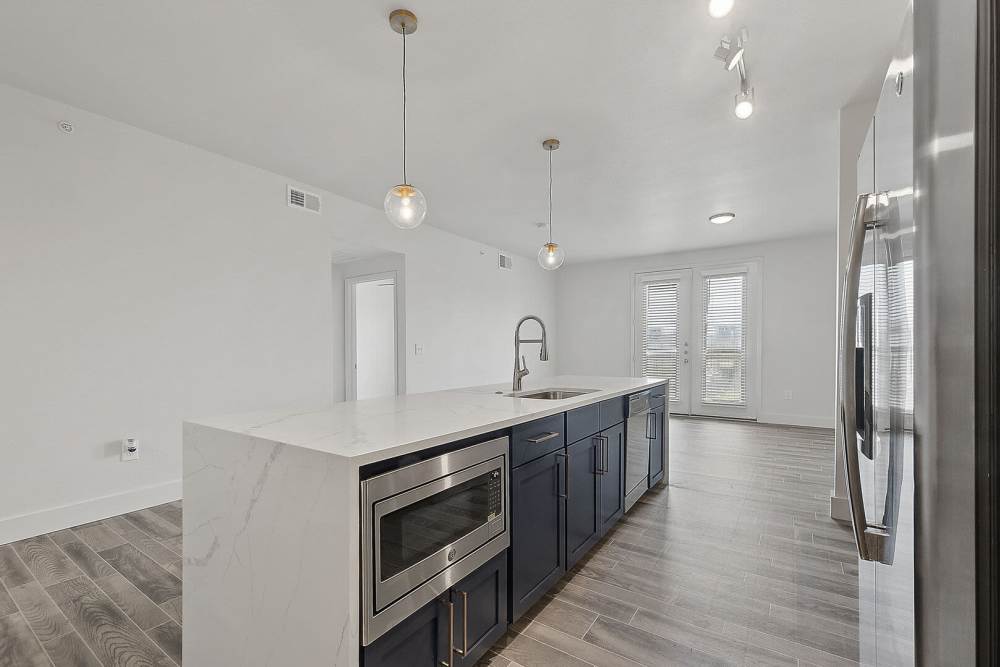 Spacious island kitchen with built-in microwave and wood-style flooring at The Lofts At West 7th in Fort Worth,Texas