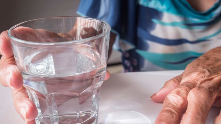 Glass of water held by elderly woman