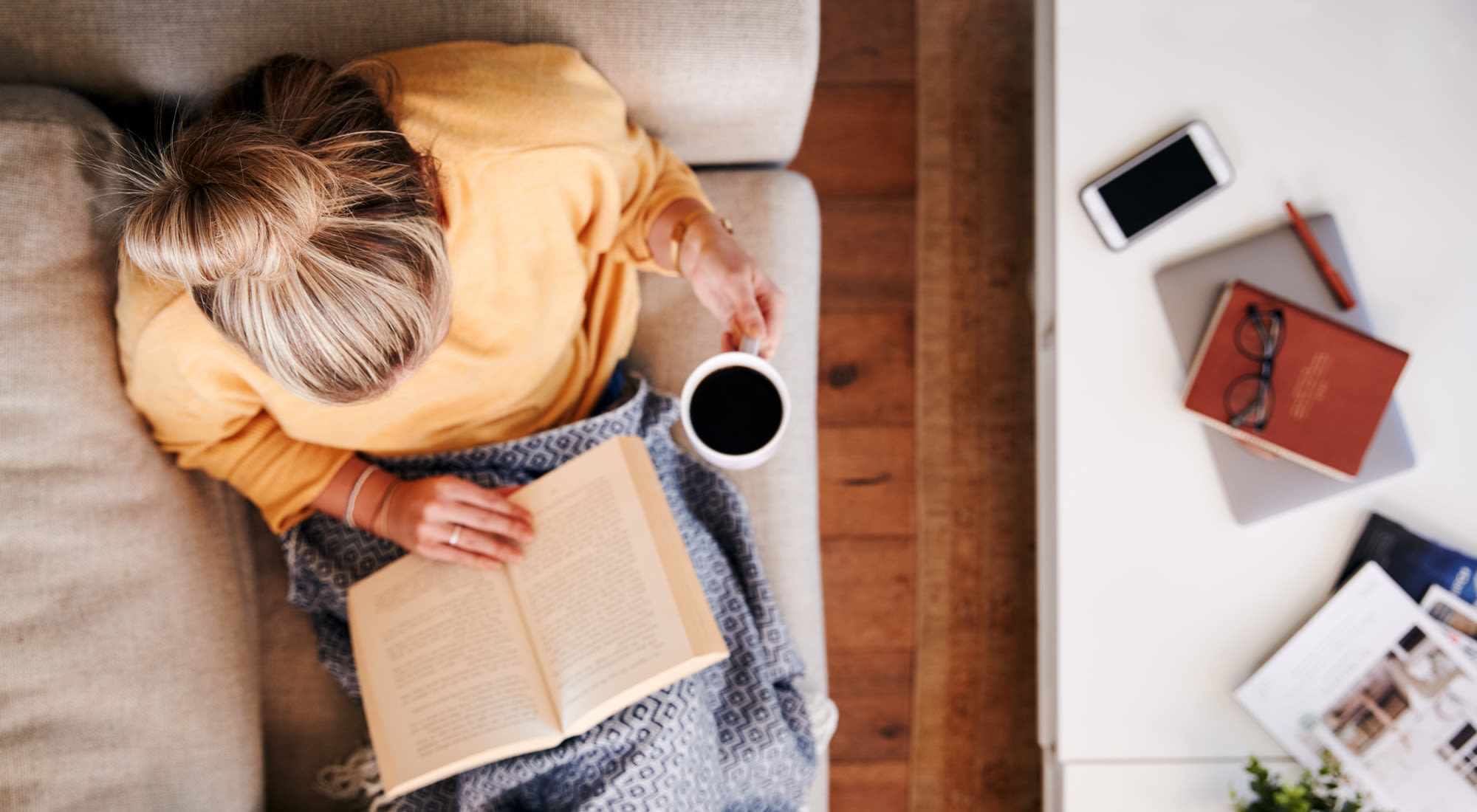 A woman reading a book while seated on a couch at Granite Creek in Rocklin, California.