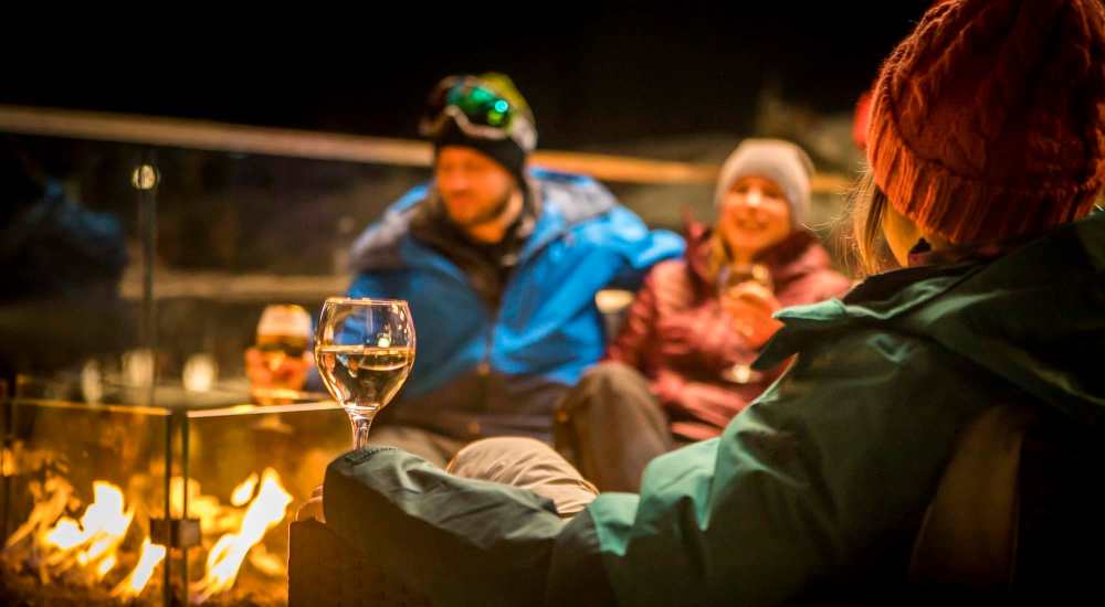 Friends enjoying drinks around afire pit near Haggerty Lane in Bozeman, Montana