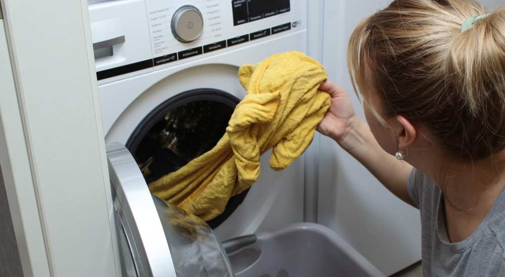 Woman using washer and dryer at Coral Wood Court in Reseda, California