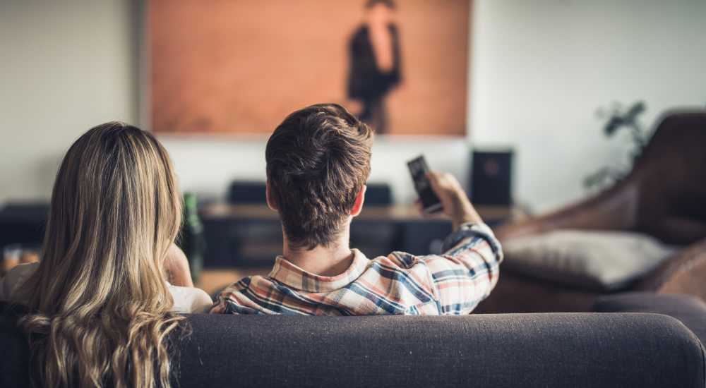 Resident couple watching TV in their new apartment home at Los Flamboyanes in Rochester, New York
