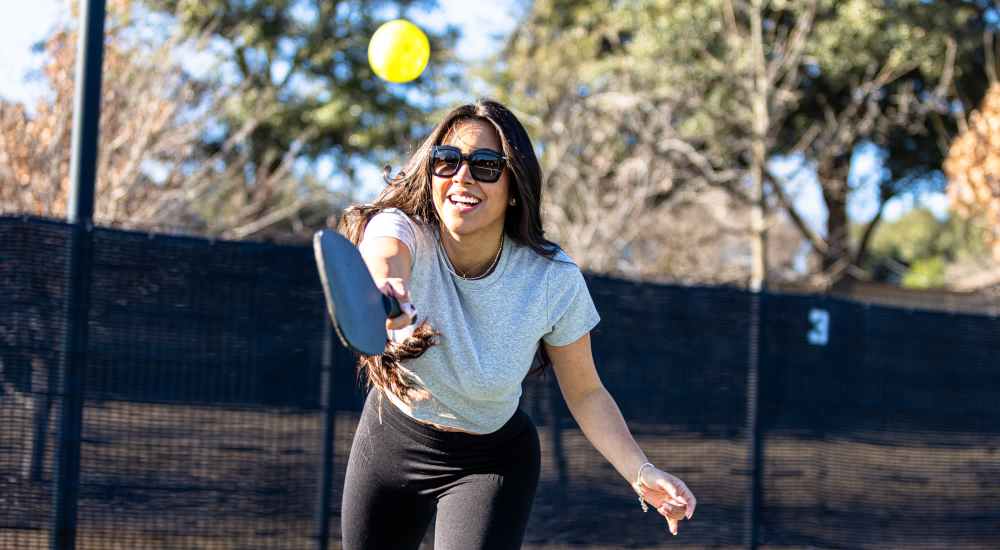 Woman playing pickleball outdoors at Sagamore Apartments in Benbrook, Texas 