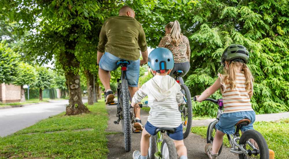 Family biking on a tree-lined path near August Friendswood in Friendswood, Texas
