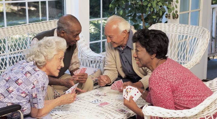 Two couples of seniors playing cards together