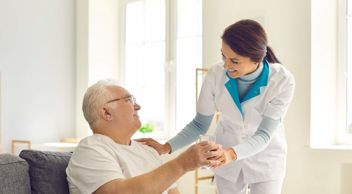 Caregiver handing senior man a glass of water