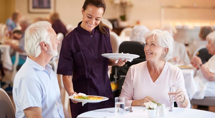 Server serving food to senior couple