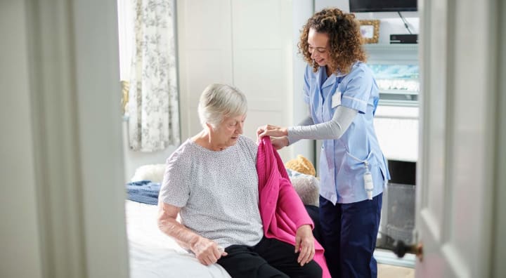 Caregiver assisting senior woman with cardigan