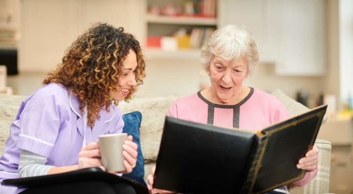 Senior woman showing her caregiver a photo album