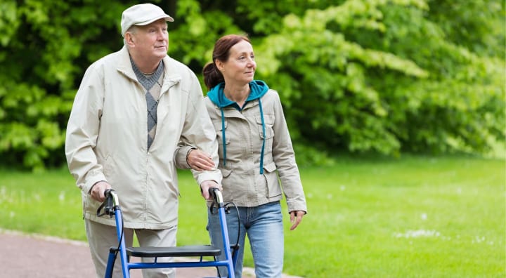 Senior man walking outside with caregiver