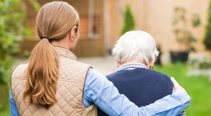 Adult daughter with arm round senior woman