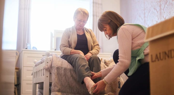 Caregiver assisting senior woman putting on shoes