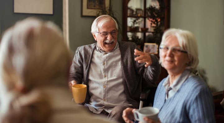 Senior man laughing while drinking tea with senior woman