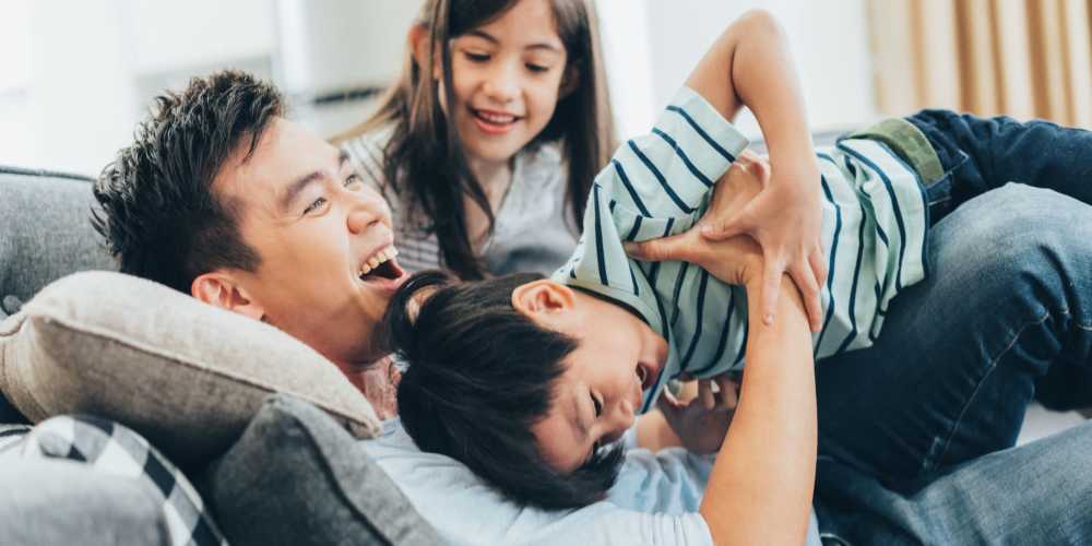 Kids playing with their father on the living room couch in their apartment at Stadium Loft Apartments in Saint Louis, Missouri