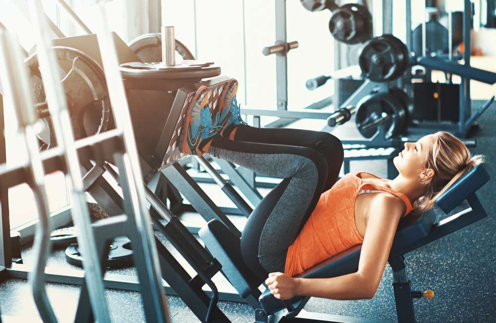 Woman exercising on leg press at luxury gym at Icon Park in Sterling Heights, Michigan 