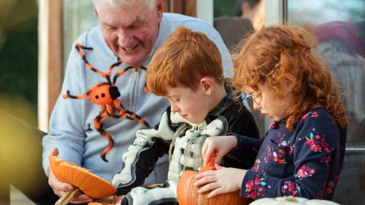 Senior carving pumpkins with grandchildren  