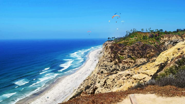 View of ocean with paragliders in background
