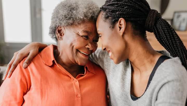 picture of smiling older mom and daughter with foreheads touching