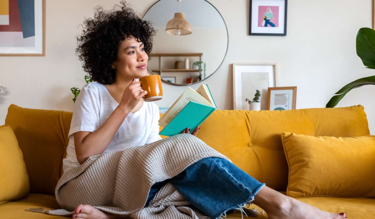 Resident with a book having coffee in her apartment living room at Earle Residences in Chicago, Illinois