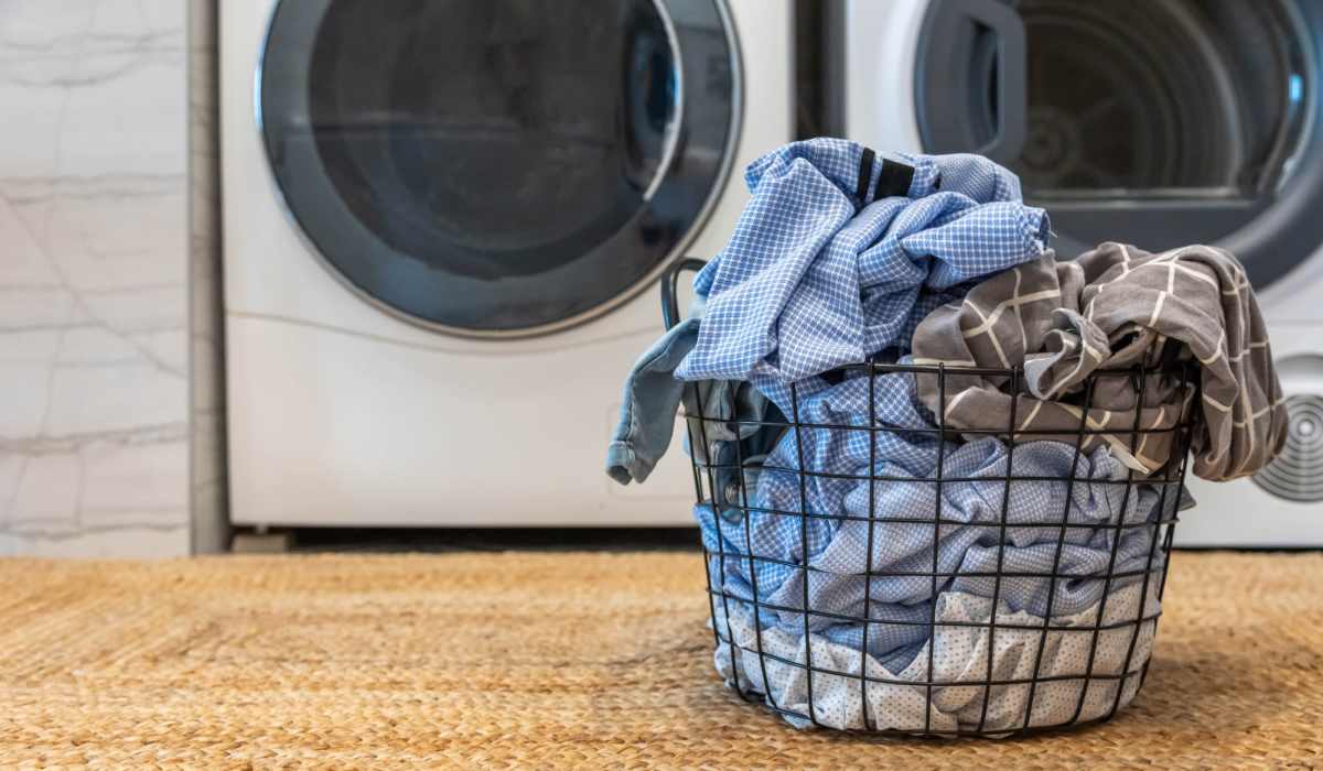 Laundr\y basket full of clothes near a washing machine and dryer at Attain Shockoe, Richmond, Virginia