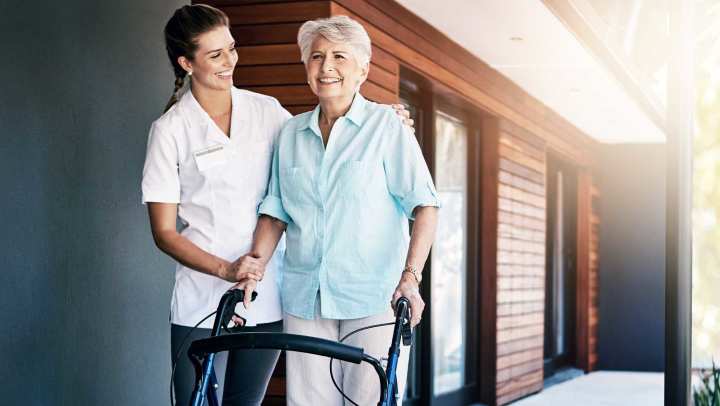 Senior woman receiving mobility assistance with a female therapist