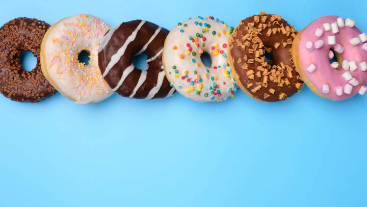 A series of colorful assorted donuts on a light blue background.