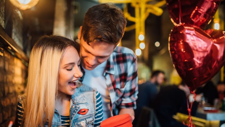 Happy young woman receiving a present from a man