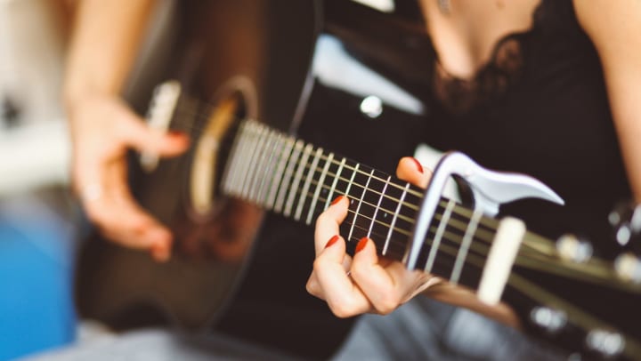Resident skillfully playing guitar in her new home at Olympus Steelyard in Chandler, Arizona