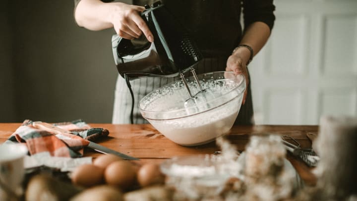 Woman preparing whipped cream with a hand mixer.