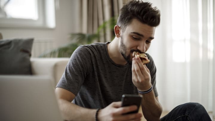 Man eating while looking at a smartphone