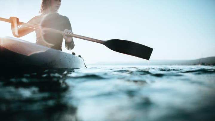 A woman paddling in a canoe in open water