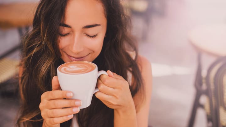A young woman enjoys a cappuccino in a coffee shop.