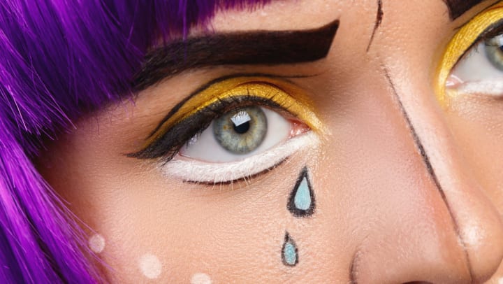 Close-up of woman’s face with anime-style makeup and purple hair.