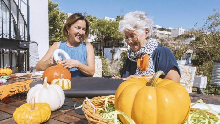 Senior woman crafting with pumpkins for halloween