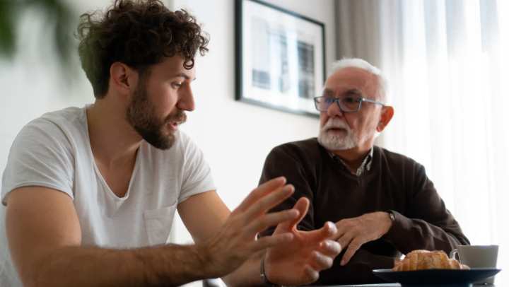 Younger man talking to an elderly man at {{location_name}} in {{location_city}}, {{location_state_name}}