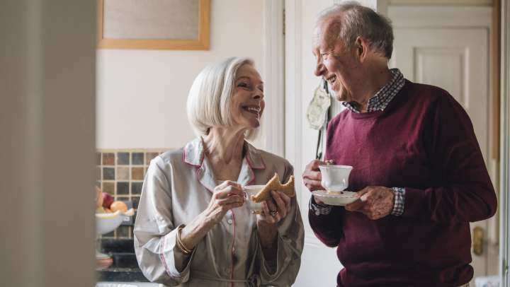 Two older adults in kitchen sharing tea and toast, supporting independent living, {{location_name}} in {{location_city}}, {{location_state_name}}