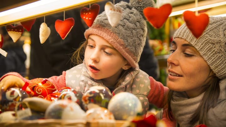A woman and her young daughter look at holiday ornaments at a flea market. 