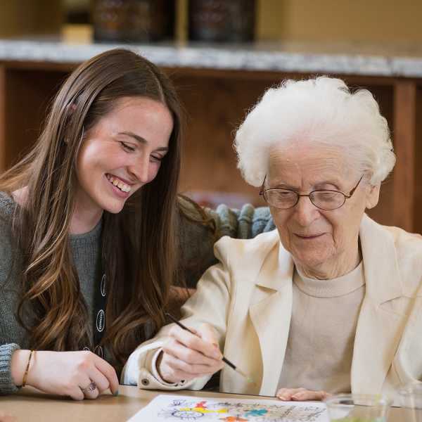 Memory Care resident painting with caregiver.