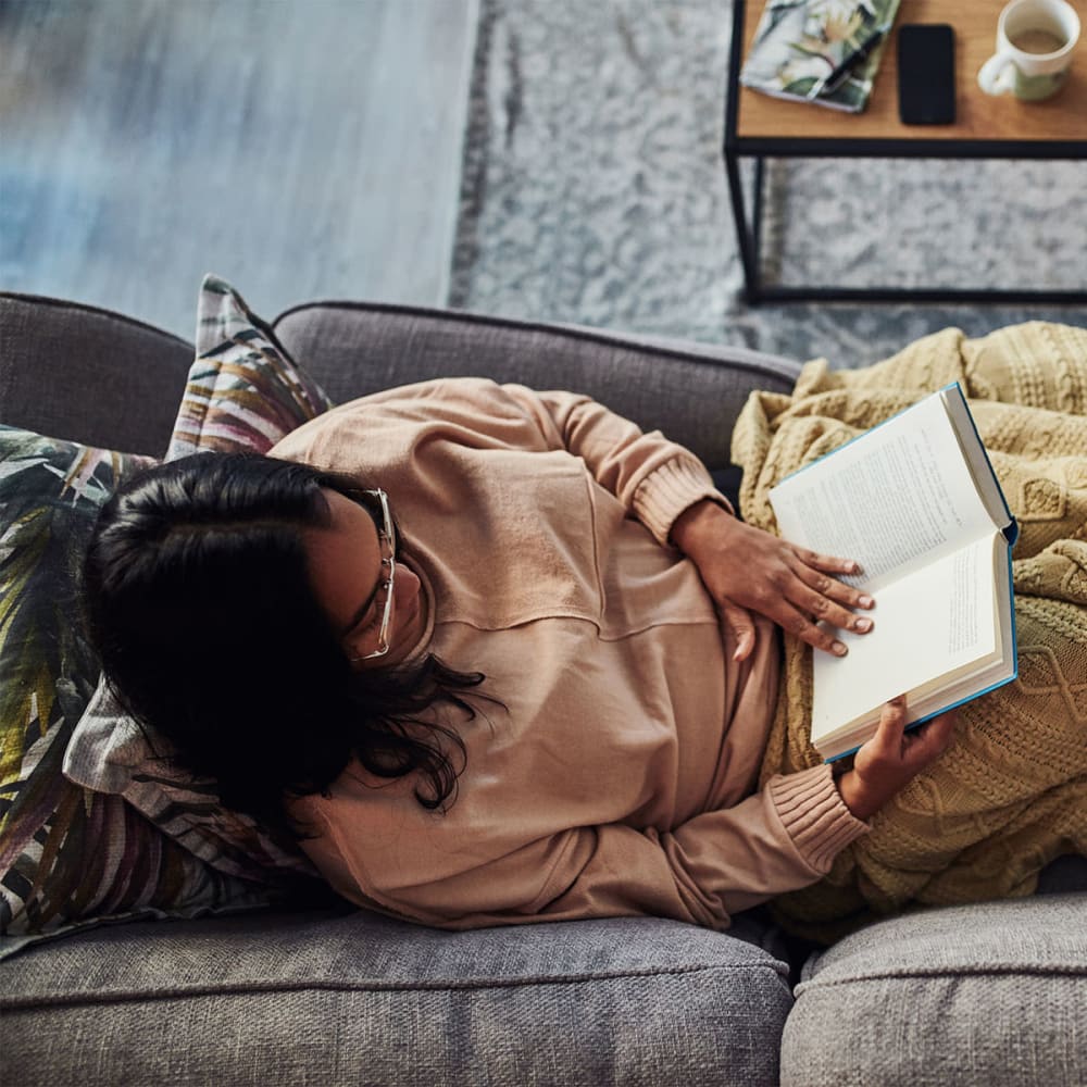 Resident unwinding with a good book on the couch in her apartment at Mission Rock at Sonoma in Sonoma, California