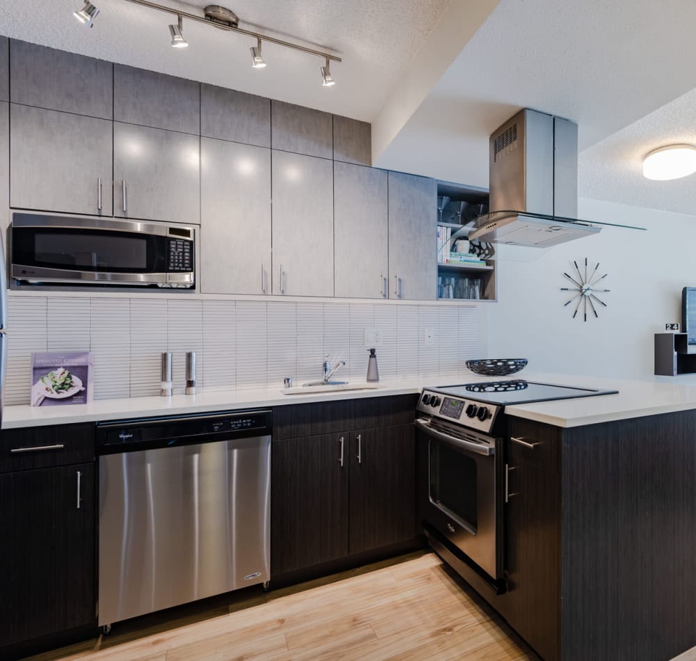 Modern kitchen with quartz countertops and rich, dark wood cabinetry in a model home at Tower 801 in Seattle, Washington