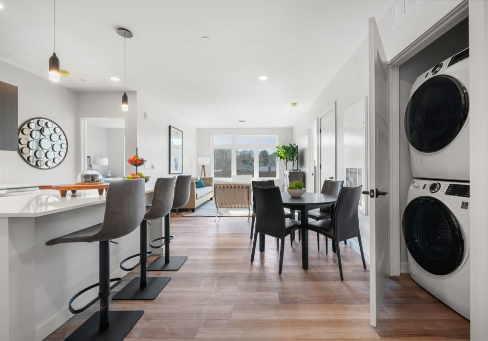 Kitchen and dining areas with a closeted full-size washer and dryer in a model apartment at Anden in Weymouth, Massachusetts