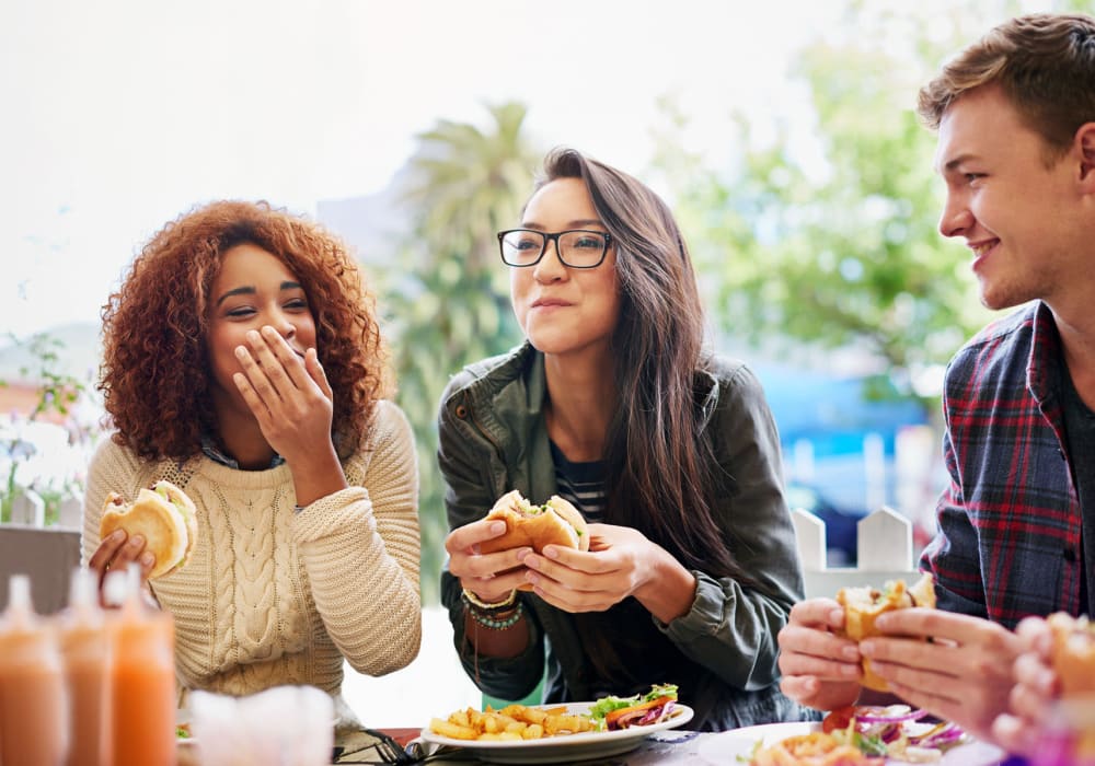 Friends eating burgers near Allina La Jolla in San Diego, California