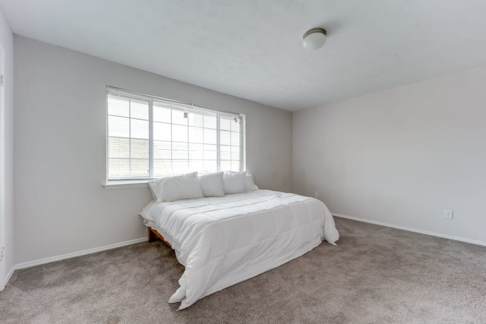 Large primary bedroom with plush carpeting and a bay window in an apartment at Sedgefield in Marietta, Georgia