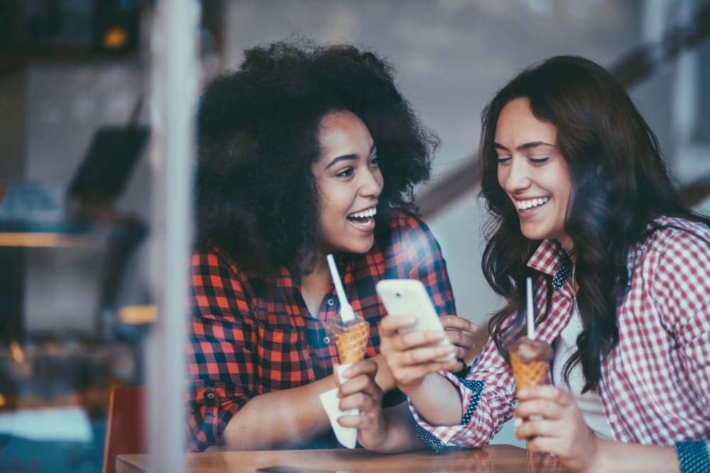 Friends eating ice cream at a local parlor and checking out our website on mobile phones near The Retreat at Arden Village Apartments in Columbia, Tennessee