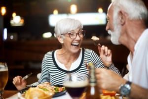 A smiling couple eating in the dining room at Mariposa at Bay Colony in Dickinson, Texas