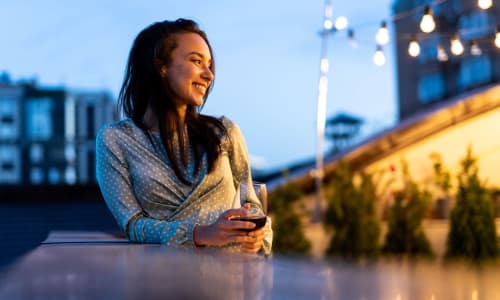 A woman enjoys a drink on her private balcony at Lakeshore Apartments in Concord, California
