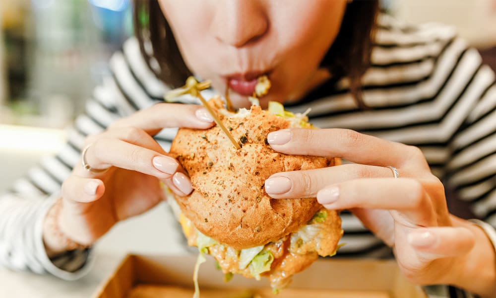 A woman biting into a burger near River Crossing in Charlotte, North Carolina