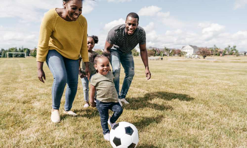 Family playing soccer in open field near A.L. Miller Village in Macon, Georgia