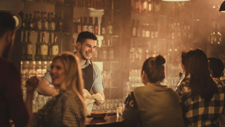 Bartender smiling at a group of customers sitting at the bar