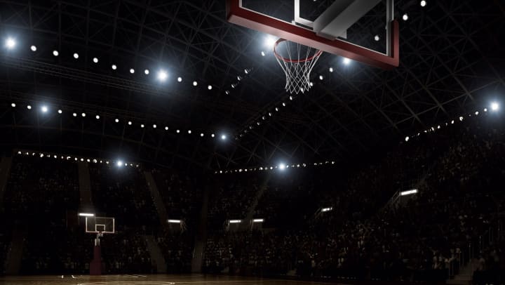 Flood-lit basketball arena full of spectators